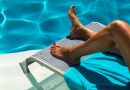 Fotografia delle gambe abbronzate di una donna sdraiata su un lettino accanto ad una piscina